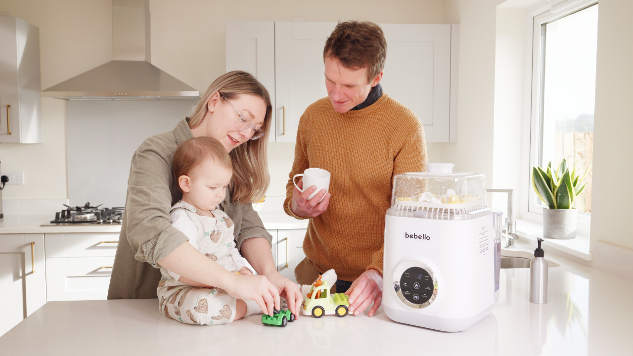 Bebello parents playing with baby on kitchen countertop next to Bebello Washer