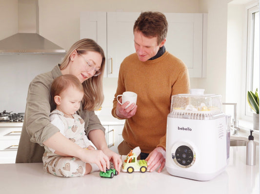 Mum, Dad playing with baby sitting on the kitchen counter with Bebello Washer next to them