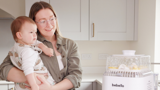 Parent and baby watching as bebello washer sterilises baby bottles and breast pump parts